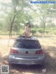 A woman sitting on the back of a silver car.