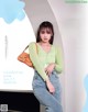 A woman in a green sweater and jeans posing for a magazine.