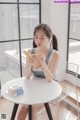 A woman sitting at a table eating a banana.