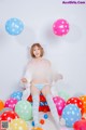 A woman sitting on top of a pile of colorful balloons.