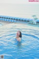 A woman in a swimming pool with the ocean in the background.