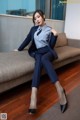 A woman in a blue suit sitting on a couch.