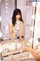 A woman standing in front of a mirror in a bathroom.