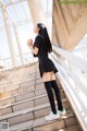 A woman in a school uniform is standing on some stairs.