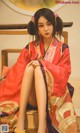 A woman in a red kimono sitting on a wooden bench.