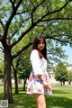 A woman standing in front of a tree in a park.