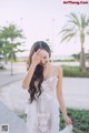 A woman in a white dress standing on a sidewalk.