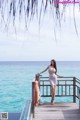 A woman in a white dress standing on a wooden dock.