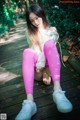 A young woman sitting on a wooden walkway in the woods.