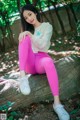 A woman sitting on a rock in a park.