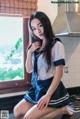 A woman in a school uniform sitting on a kitchen counter.