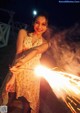 A woman holding a sparkler in her hand at night.