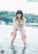 A woman in a white bikini standing in the water.