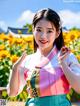 A woman in a colorful dress standing in front of a field of flowers.