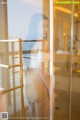 A woman in a white bikini standing in a shower.